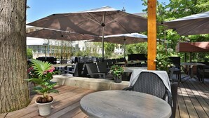 An outdoor patio with wooden tables and chairs, large umbrellas, and potted plants. - Hotel Central (Frankenthal)