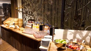 A buffet setup with wicker baskets, a variety of beverages, and fruit bowls. - Hotel Central (Frankenthal)