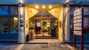 The entrance of Hotel Central with a glass door, illuminated by overhead lights, and a signboard listing amenities. - Hotel Central (Frankenthal)