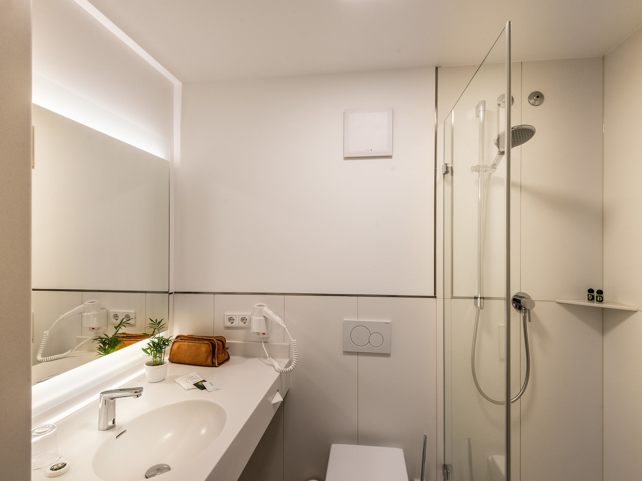 Une salle de bain moderne avec un grand miroir, un lavabo et une douche à parois de verre.