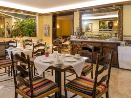Un'area dedicata alla ristorazione con tavoli apparecchiati, sedie in legno e un'area buffet.