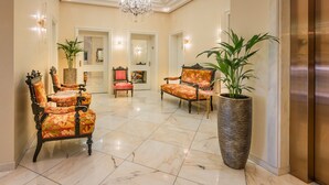 Eine geräumige Lobby mit hoher Decke, einem Kronleuchter und einer großen Pflanze in einem Topf.