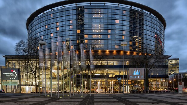 Un edificio moderno con fachada de vidrio circular, entrada visible y un cartel que dice 'Congress Center Munich'.