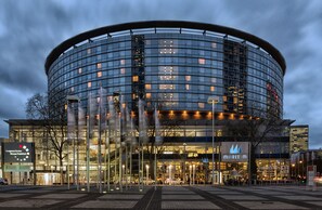 Ein modernes Gebäude mit einer kreisförmigen Glasfassade, einem gut sichtbaren Eingang und einem Schild mit der Aufschrift 'Congress Center München'.