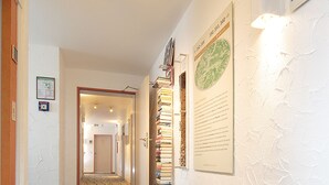 Un passadís amb sòl de pedra, una porta de fusta a l'esquerra i una paret amb plaques informatives emmarcades.