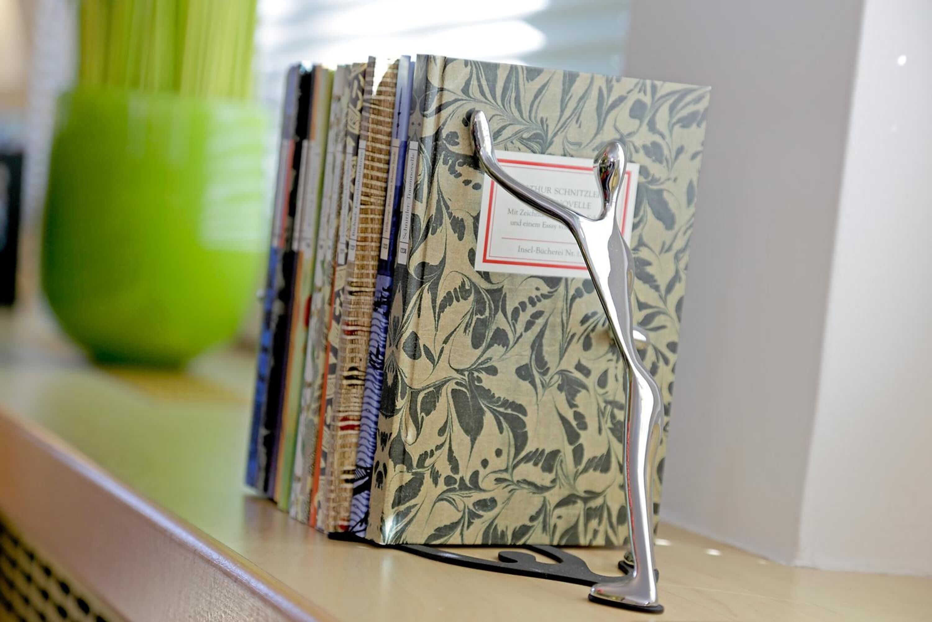 A shelf with a series of binders, each with a label and a metal clip.