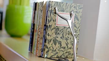 A shelf with a series of binders, each with a label and a metal clip.