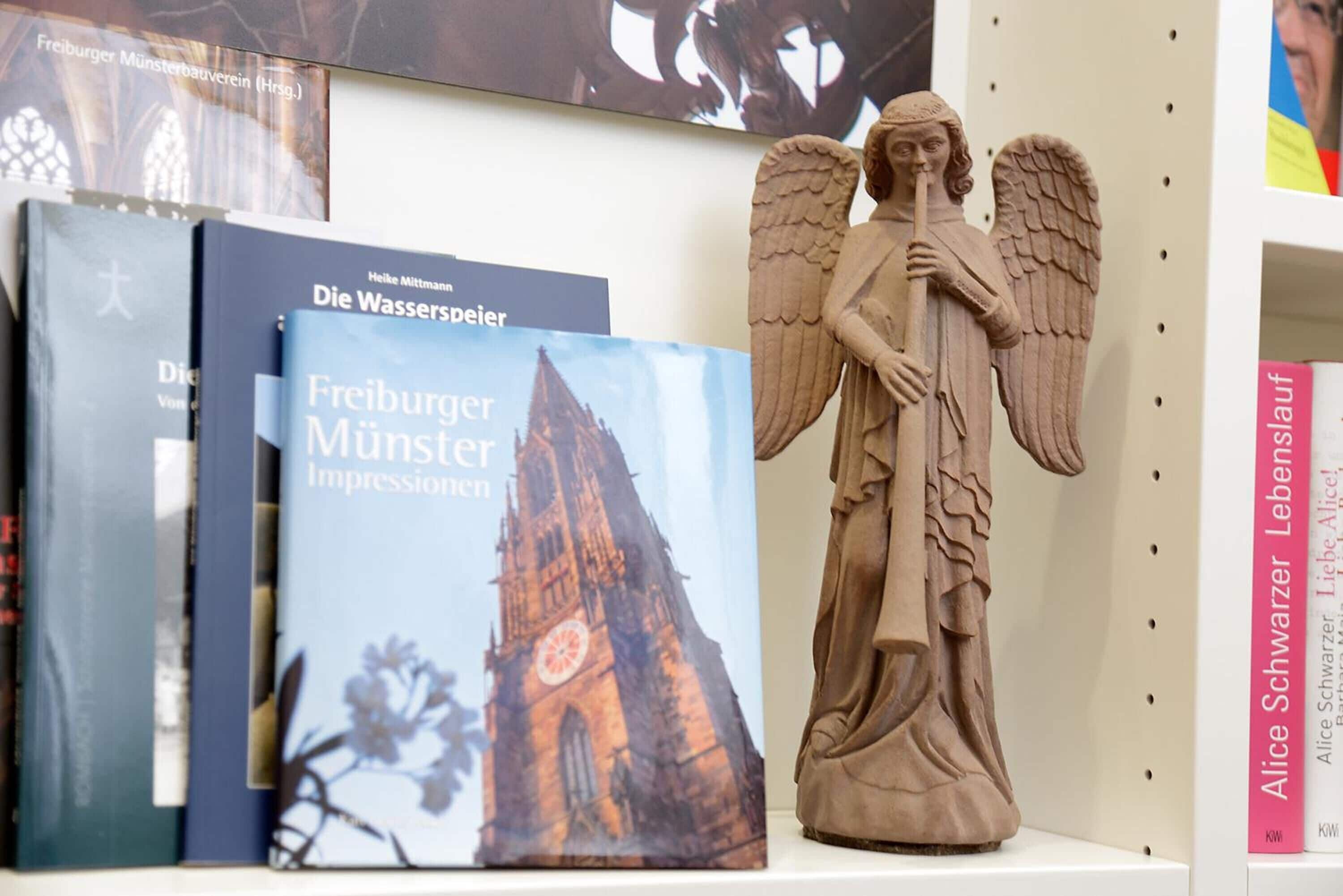 Een boekenplank met boeken en een engelbeeld.