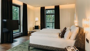 Una habitación de hotel moderna con una cama grande, un televisor de pantalla plana, un escritorio y una silla.