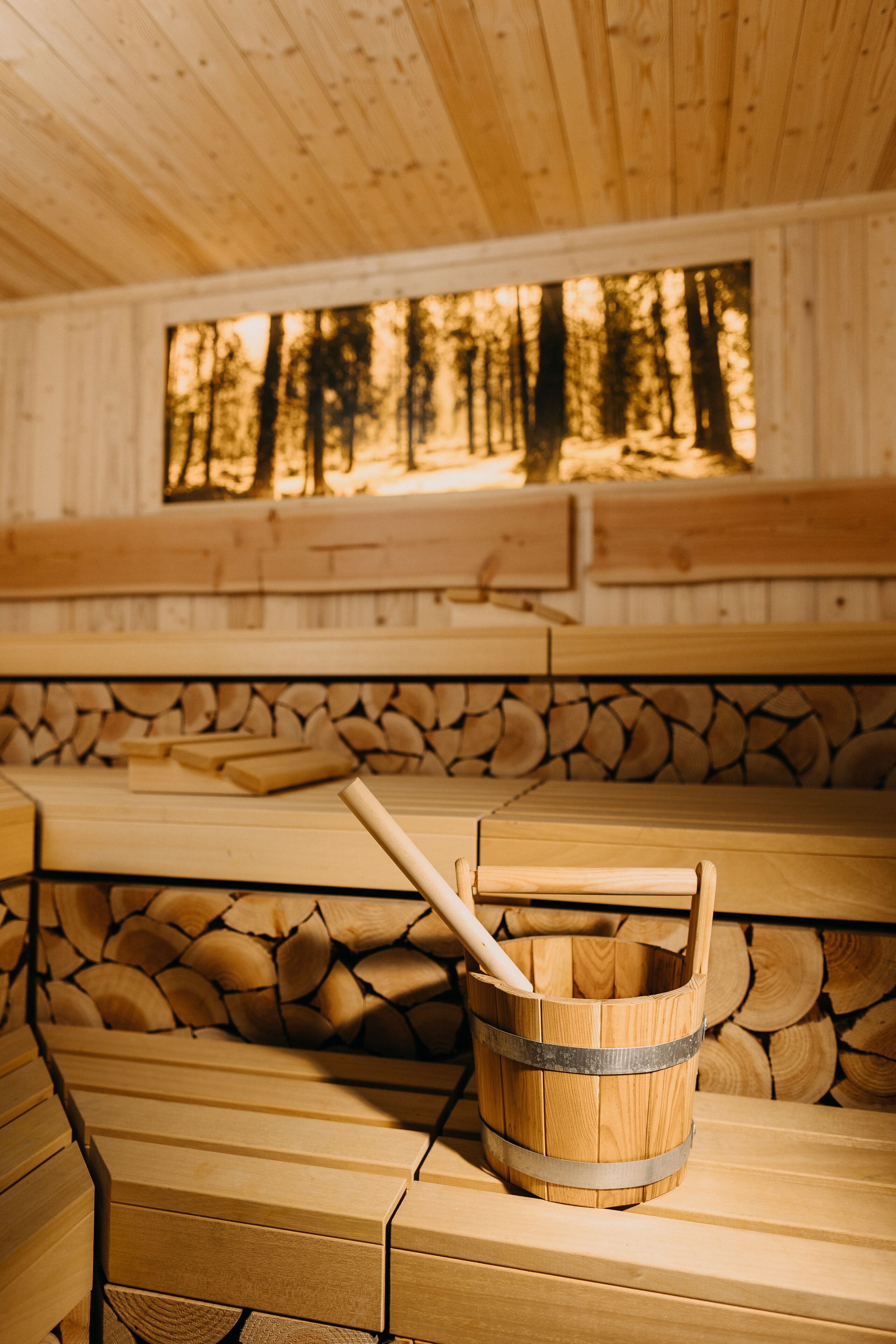 Una sauna de madera con bancos y un cubo de madera con una palanca.