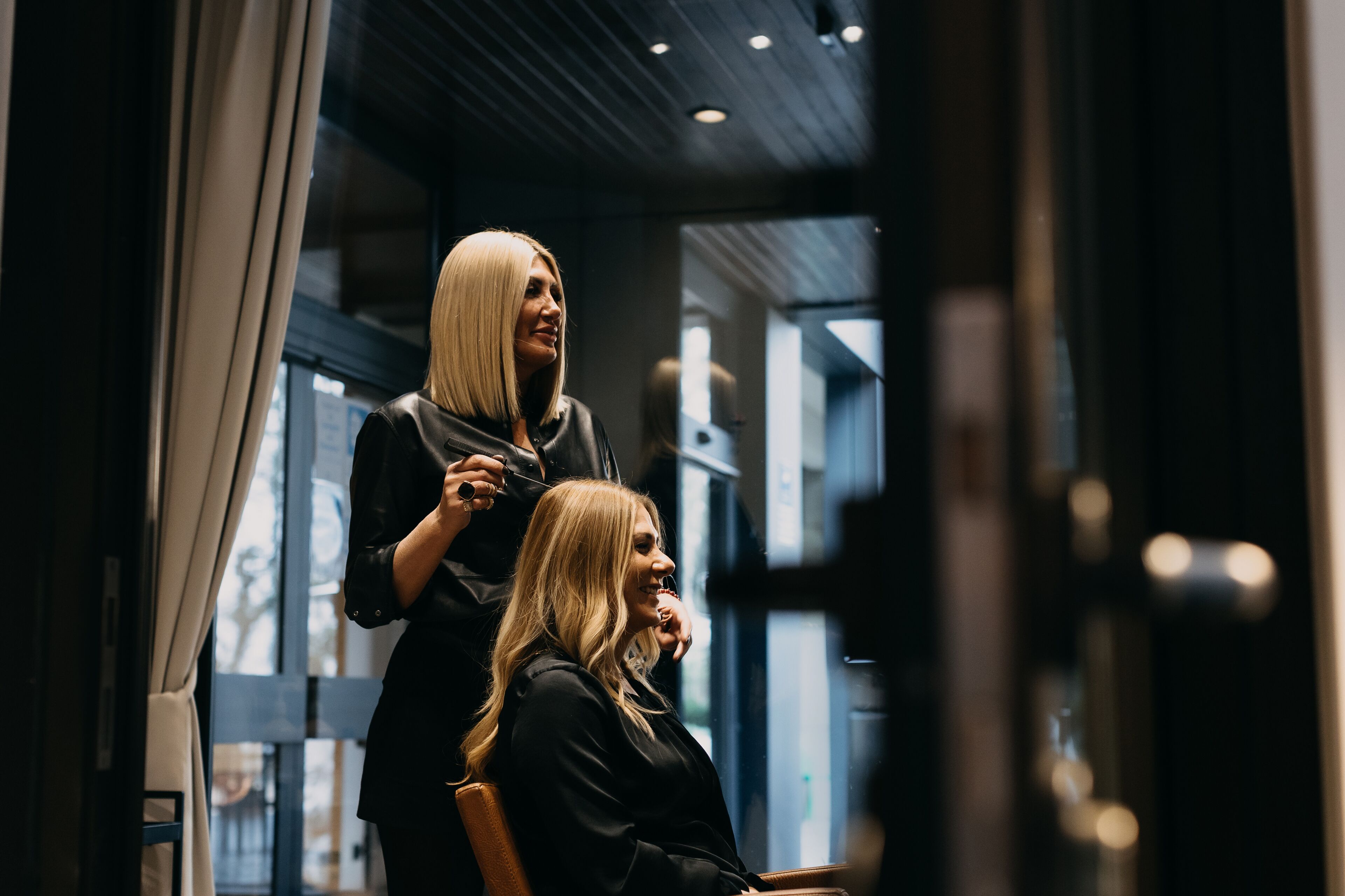 A salon interior with a modern design, featuring a large window and a mirror.