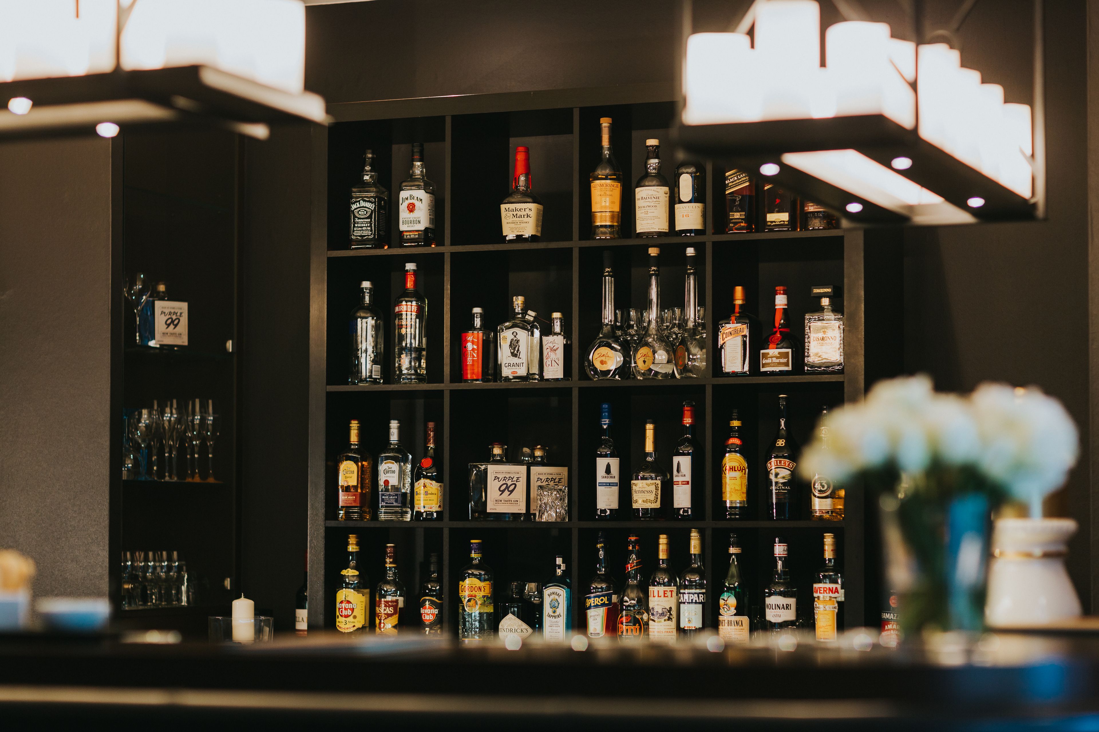 A bar area with shelves stocked with various liquor bottles and glasses.