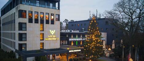 A hotel with a prominent sign, a well-maintained lawn, and a large Christmas tree.