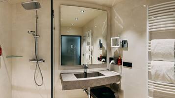 A modern bathroom with a glass-enclosed shower, a vanity with a sink, and a towel rack.