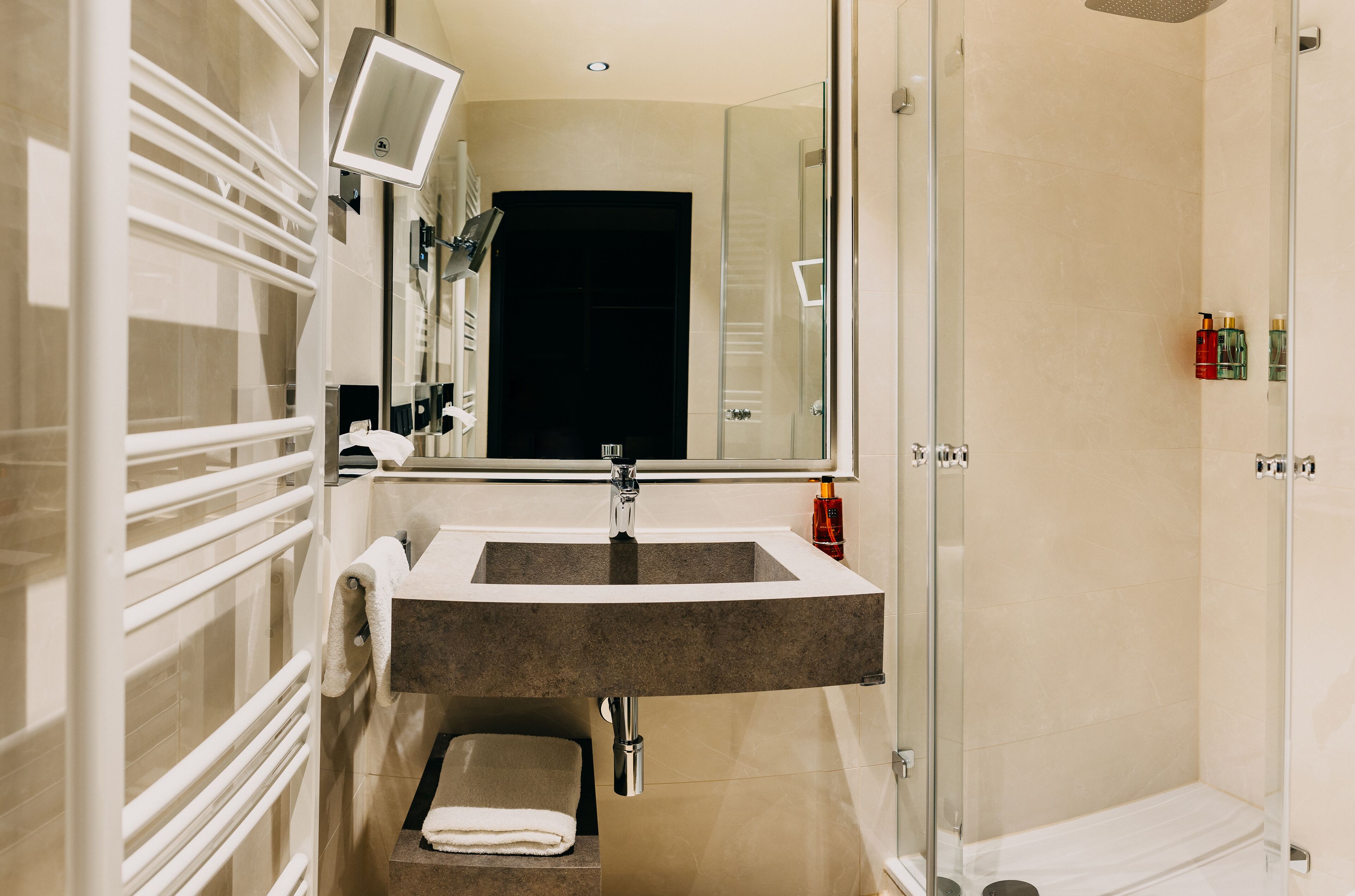 A modern bathroom with a large mirror, a sink, and a shower area.