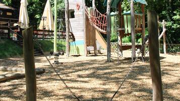 Un parque infantil con columpios, estructuras para escalar y un tobogán.