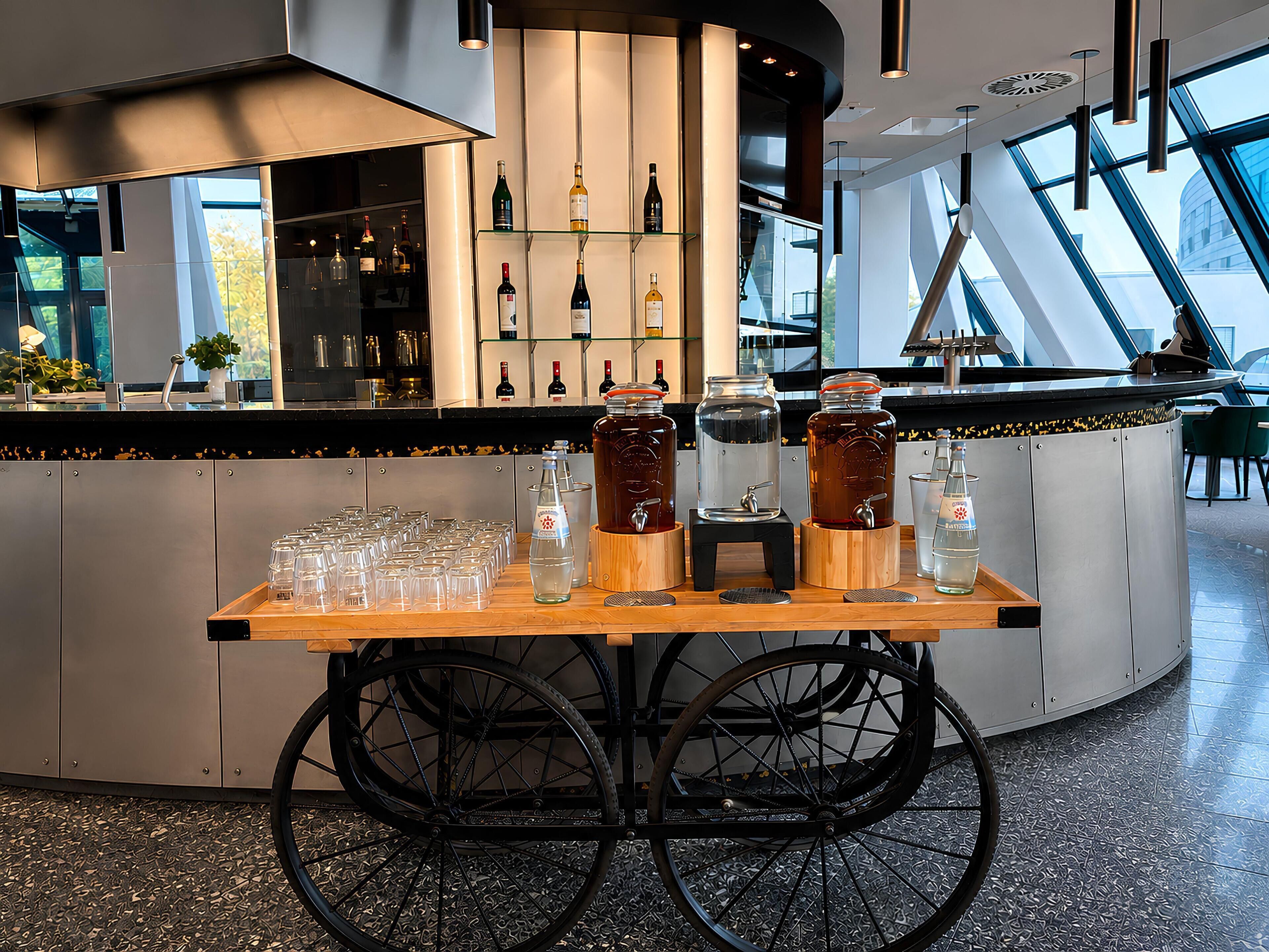 Een bar met een karretje, glazen en flessen.