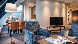 A modern hotel lobby with a large TV, comfortable seating, a dining area, and a view through a large window. - Excelsior Hotel Nürnberg Fürth, a member of Radisson Individuals (Fuerth)