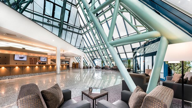 A spacious lobby with a high ceiling, modern furniture, and a reception area. - Excelsior Hotel Nürnberg Fürth, a member of Radisson Individuals (Fuerth)