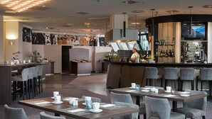 A restaurant with a bar area, multiple tables with chairs, and a chef at the bar. - Excelsior Hotel Nürnberg Fürth, a member of Radisson Individuals (Fuerth)