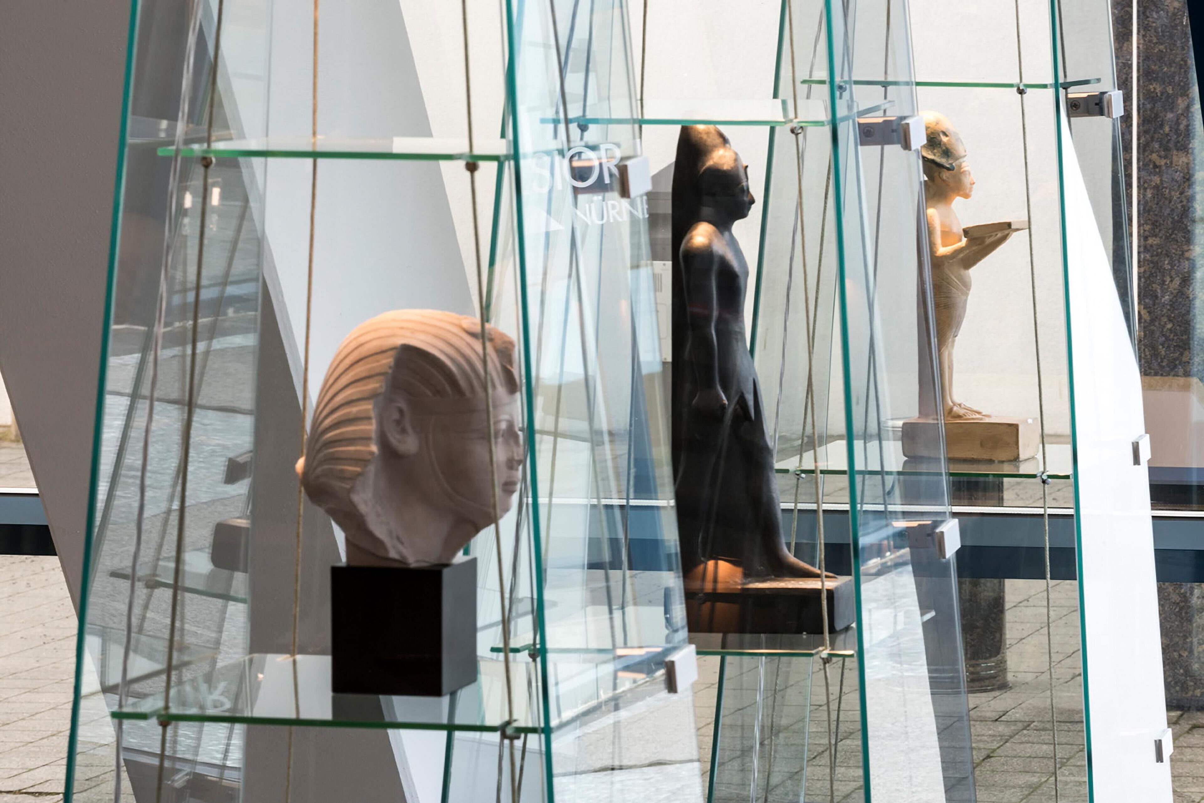 A glass display case with a bust sculpture and a statue.