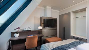 Ein Hotelzimmer mit Schreibtisch, Stuhl, Bett, Fernseher und Fenster.