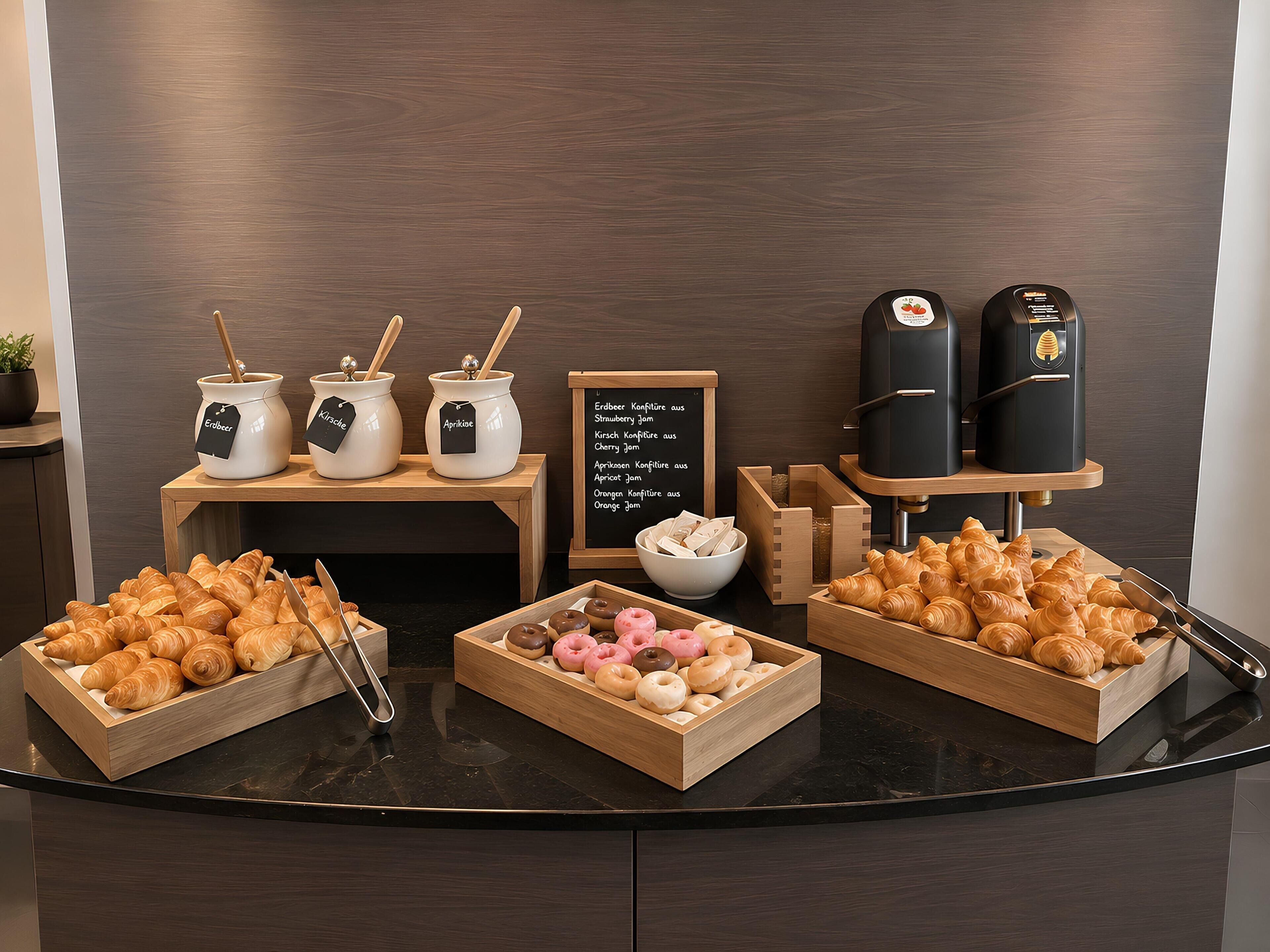 A breakfast buffet with croissants, donuts, and coffee machines.
