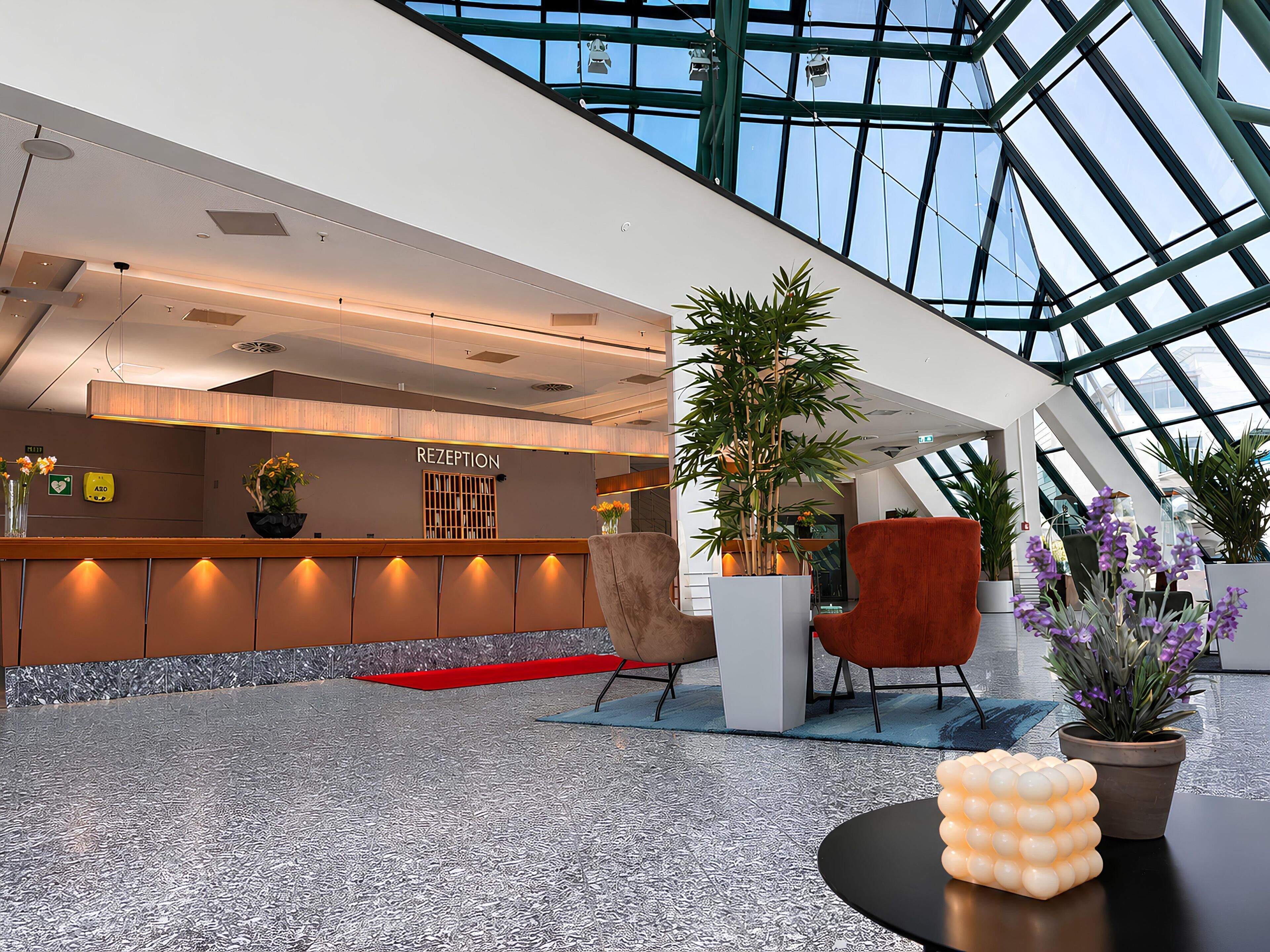 A modern reception area with a reception desk, seating, and potted plants.