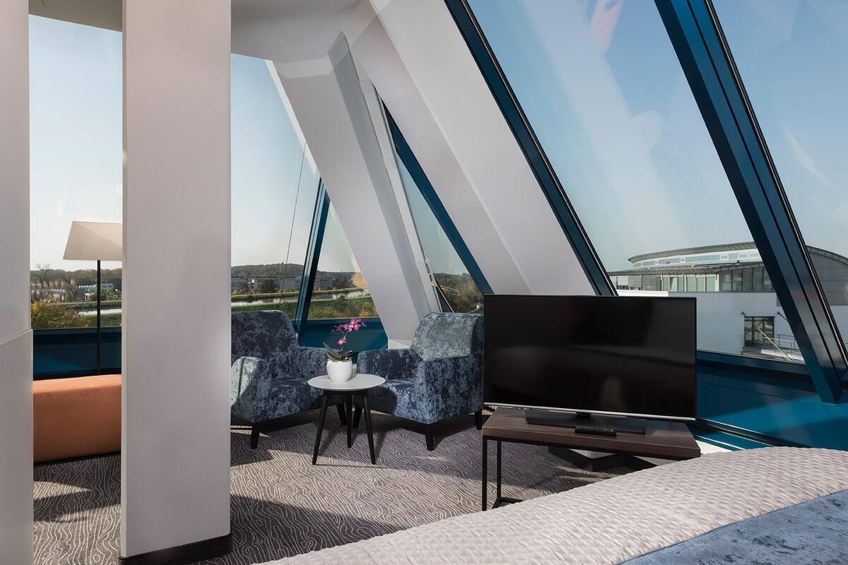 Ein modernes Zimmer mit großem Fernseher, bequemen Sitzgelegenheiten und Blick auf die Stadt.