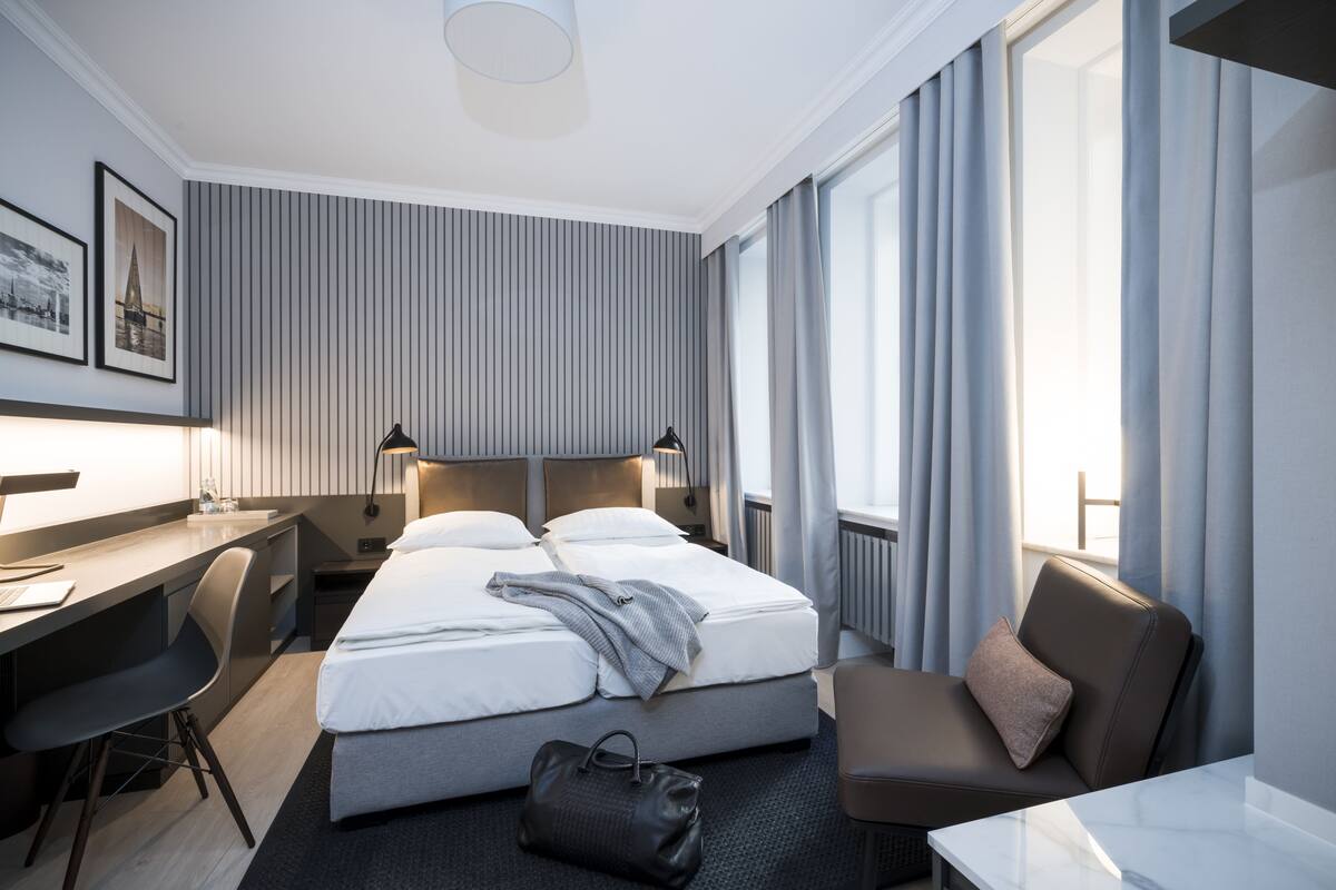 A modern hotel room with a large bed, a desk, and a chair.