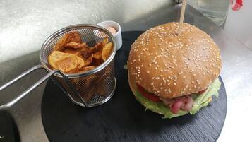 Ein Burger mit Sesam und eine Portion Pommes im Sieb.