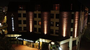 A hotel named "Panorama" with a modern brick facade and illuminated signage. - Hotel Panorama Harburg (Hamburg)