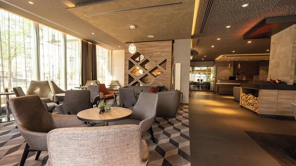 Un moderno vestíbulo de hotel con zonas de estar, una recepción y vistas al exterior.