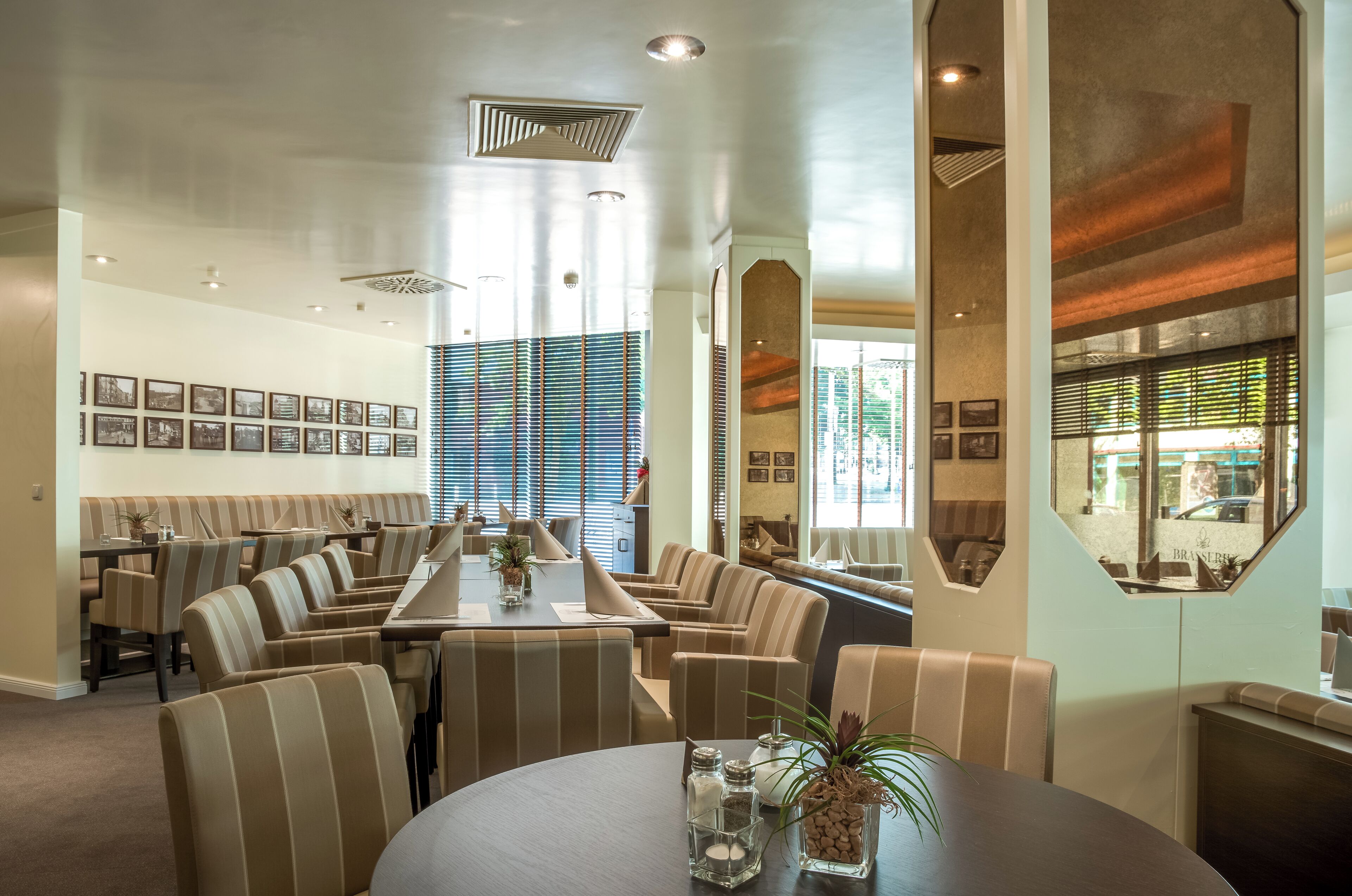 Un restaurante con cabinas a rayas, una mesa común alargada y cuadros en la pared.