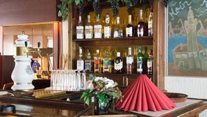 A bar area with a variety of liquor bottles, a white beer tap, and a chalkboard with a drawing. - Hotel Helgoland (Hamburg)