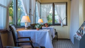 A hotel room with two tables, chairs, a lamp, and a bookshelf. - Hotel Helgoland (Hamburg)
