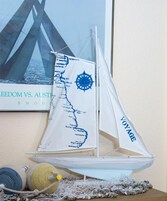 Un velero a escala con un mapa y una brújula en la vela, un mapa enmarcado en la pared y un juguete de punto en la mesa.