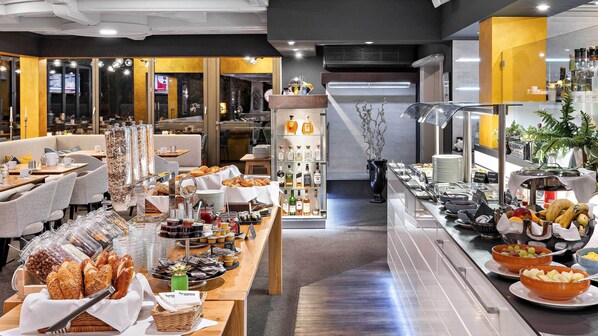 A buffet setup with various food items and beverages, a seating area with tables and chairs, and a modern interior design. - Hotel Central Hof (Hof)