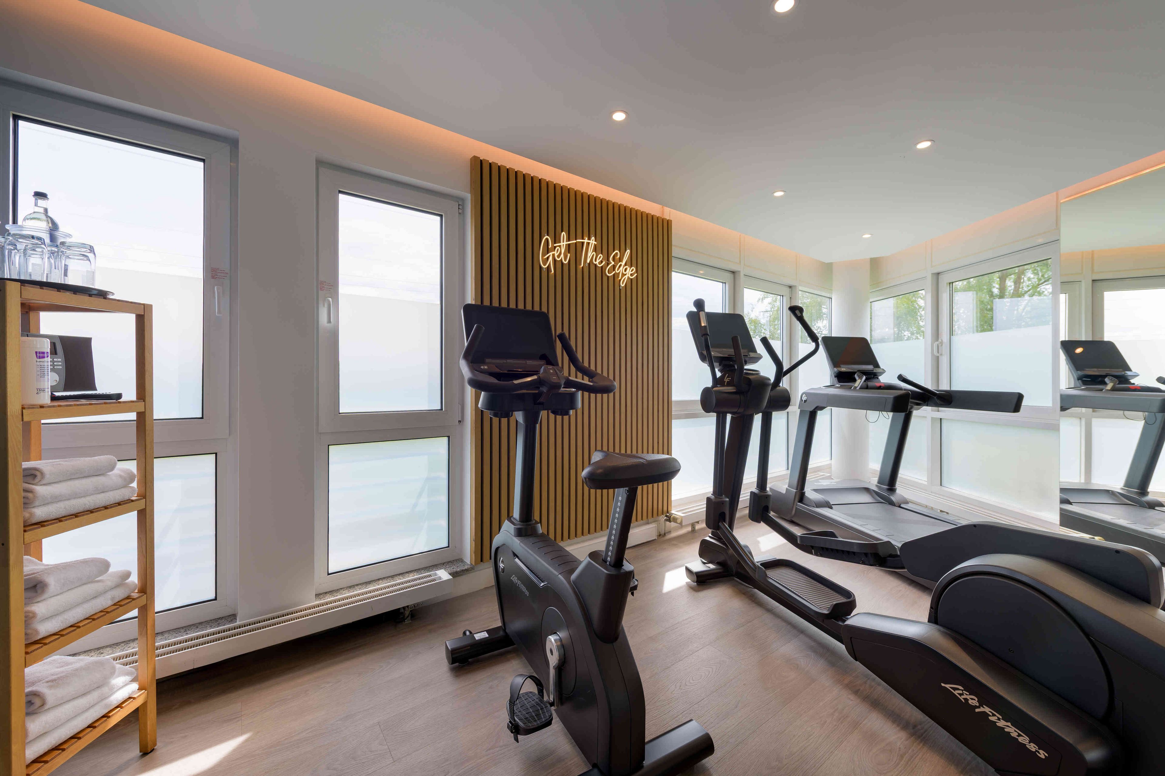 A modern gym with exercise equipment, large windows, and a motivational sign.