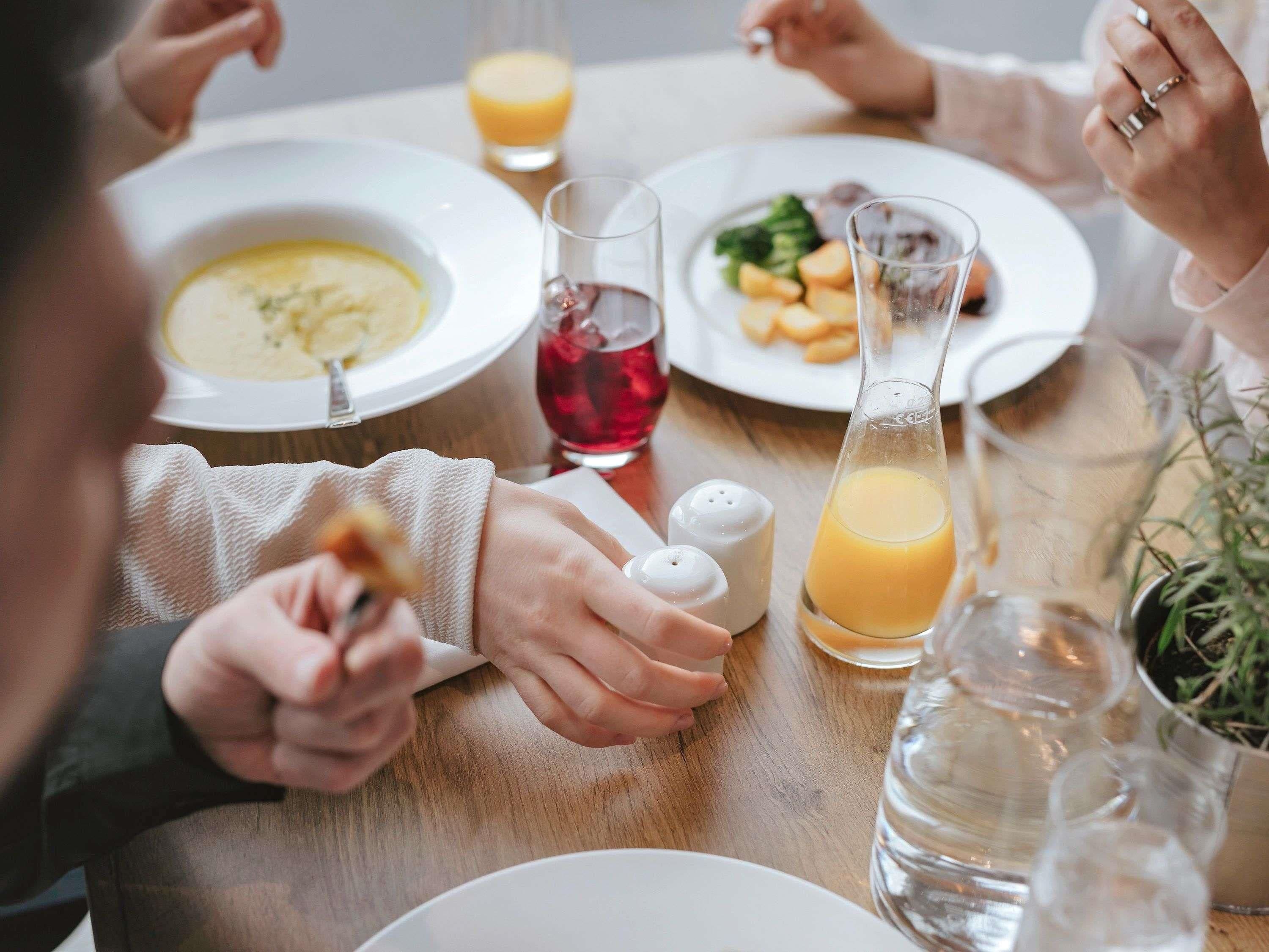 Een eettafel met borden eten, glazen en een waterfles.