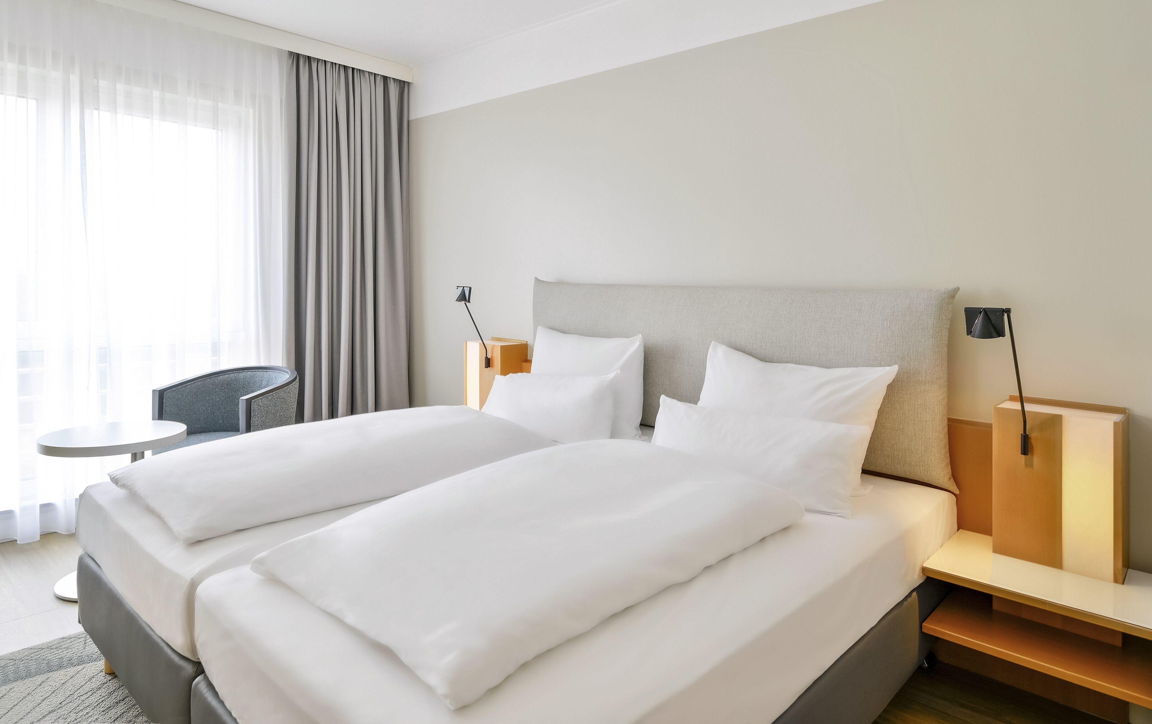 Una habitación de hotel con una cama grande, dos mesitas de noche, un escritorio y una silla.