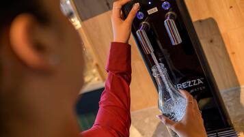 A person using a water dispenser with a bottle in hand.
