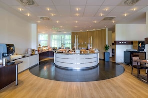 A modern breakfast area with a central counter, seating, and a coffee machine. - Mercure Hotel Kamen Unna (Kamen)