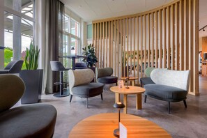 A modern lounge area with seating, a coffee table, and a wooden partition. - Mercure Hotel Kamen Unna (Kamen)