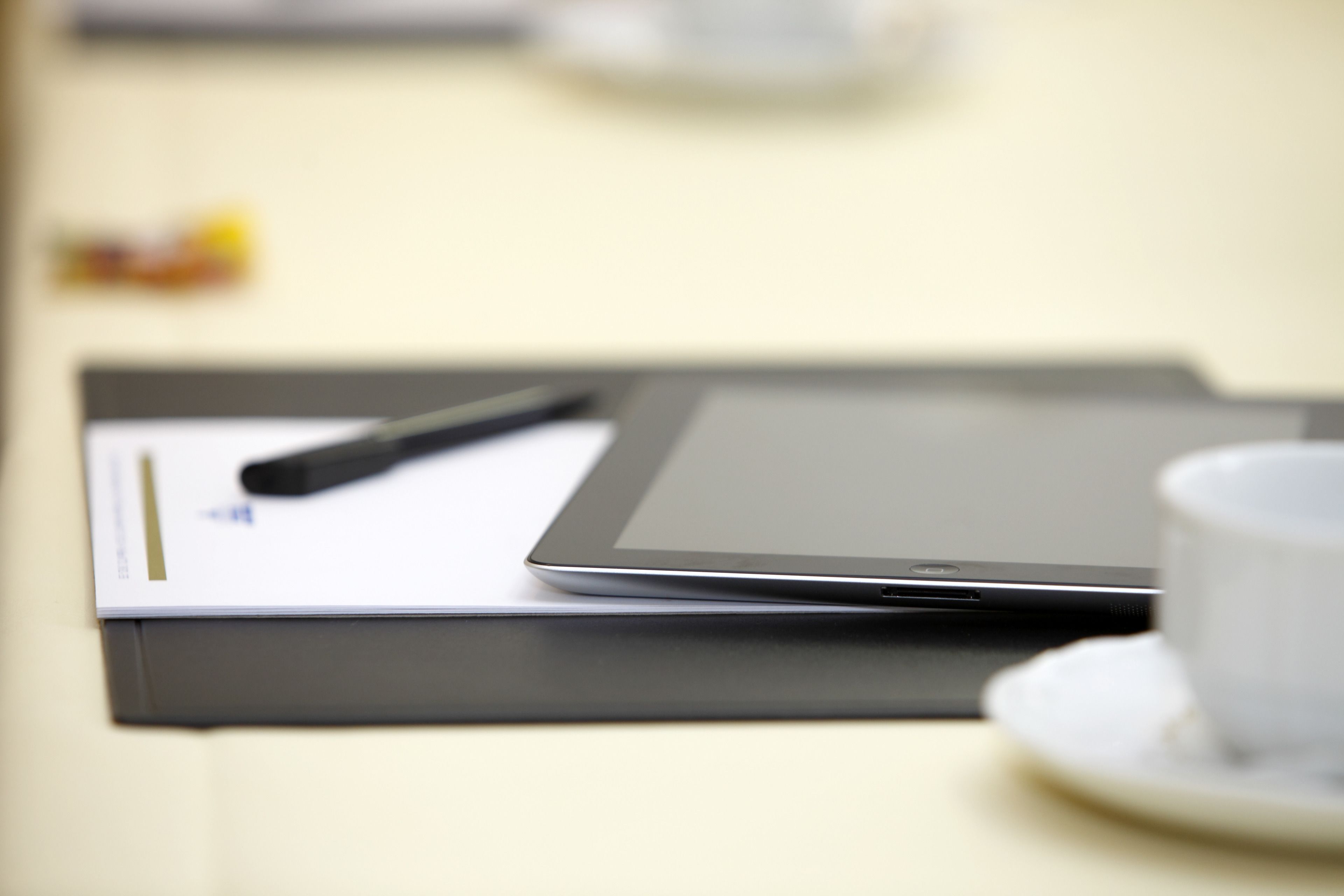 A tablet on a table with a cup and saucer.