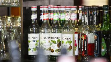 Una repisa con varias botellas de sirope Monin, incluyendo sabores como jengibre, kiwi y mango.