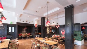 Un restaurante amplio con mesas y sillas de madera, lámparas colgantes rojas y un techo alto.