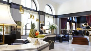 Un vestíbulo de hotel con mostradores de mármol, un mostrador de recepción y una escalera que lleva a otra zona.