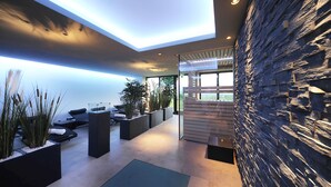 Un vestíbulo moderno con pared de piedra, zonas de estar y plantas en macetas.