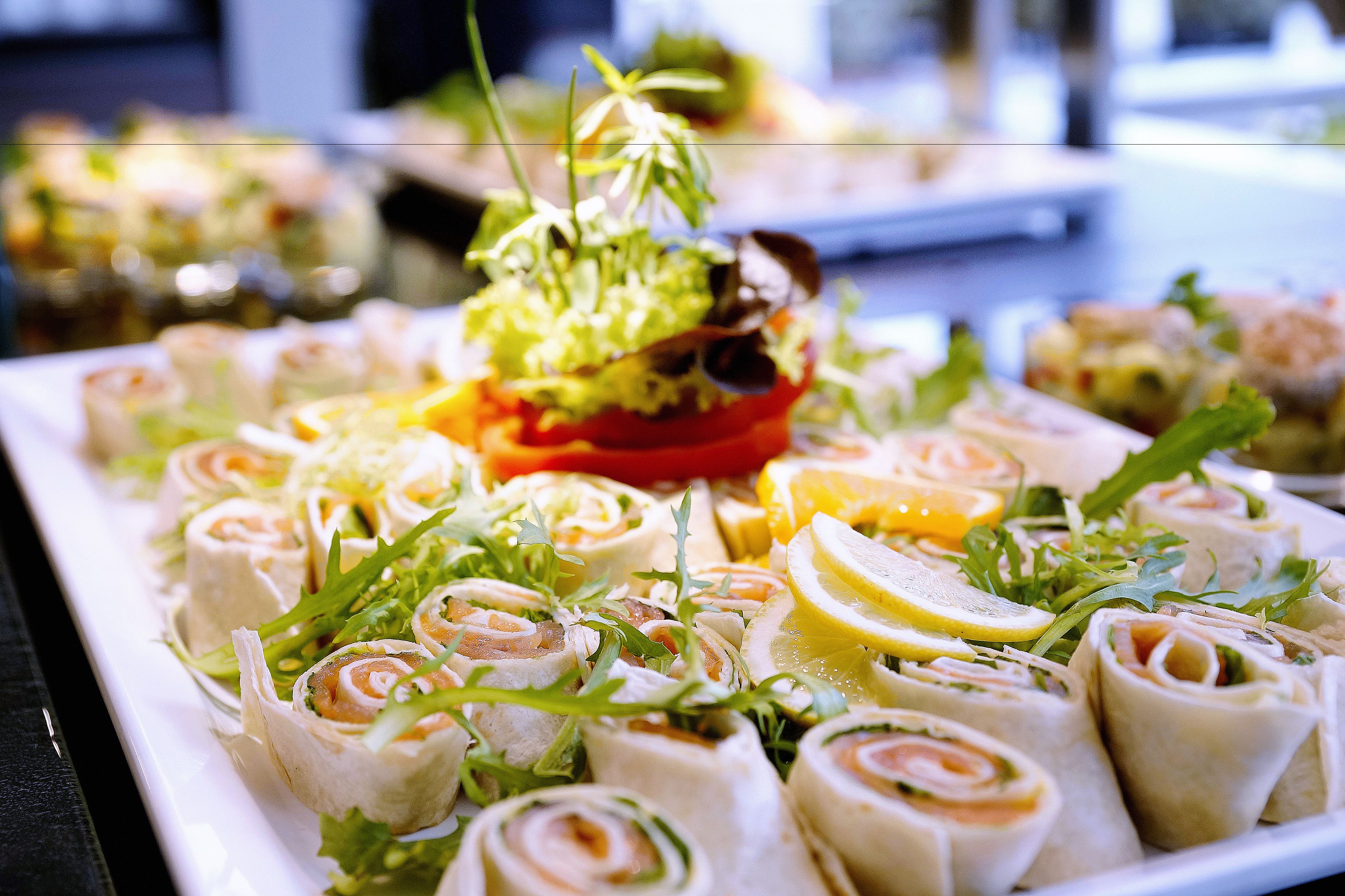 A platter of rolled appetizers garnished with greens and lemon slices.